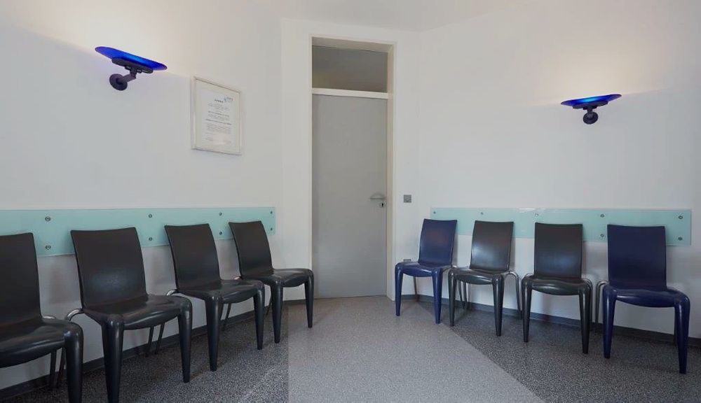 Wartezimmer mit Stuhlreihen und blauen Wandleuchten